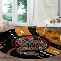 Round area rug with Aboriginal snake dot pattern, black base with orange circles and paw prints