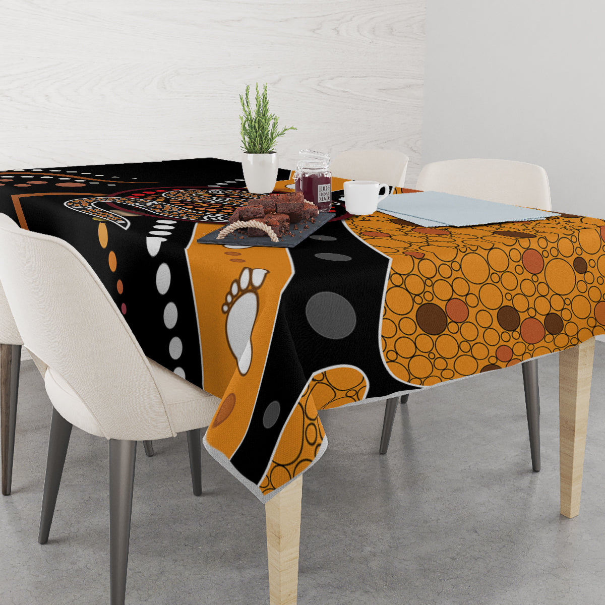 Multicolor snake dot art tablecloth draped over dining table, black and orange dotted design