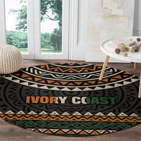 Round area rug with dark tribal design, zigzag bands, and large “IVORY COAST” lettering