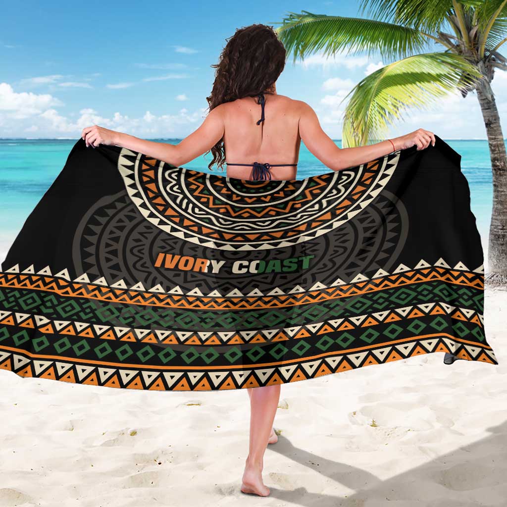 Black sarong draped over shoulders, gray and orange geometric pattern with 'IVORY COAST'