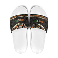 White slide sandals with multicolor geometric patterned strap and green/orange text
