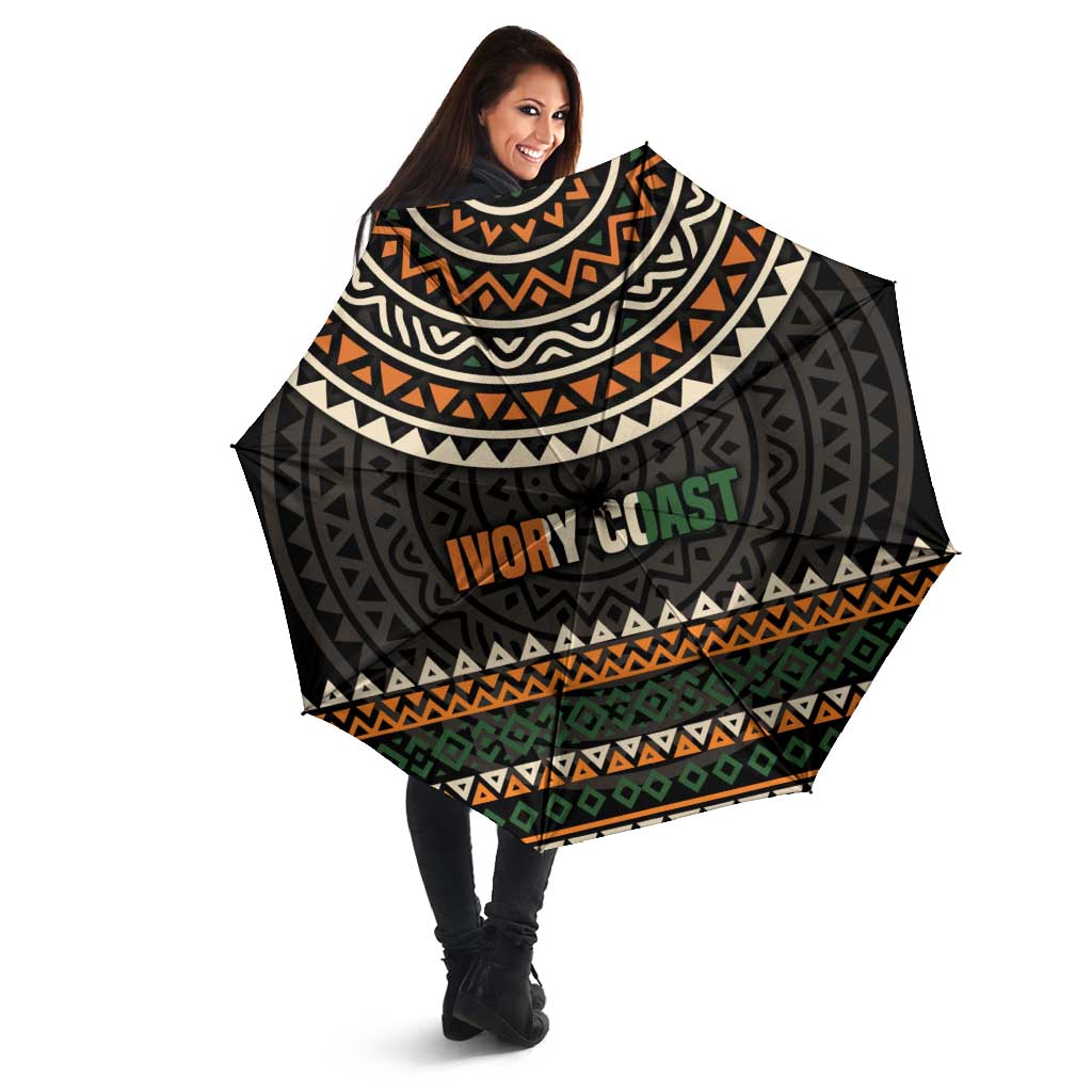 Open multicolor umbrella with black canopy, geometric bands, and 'IVORY COAST' center text