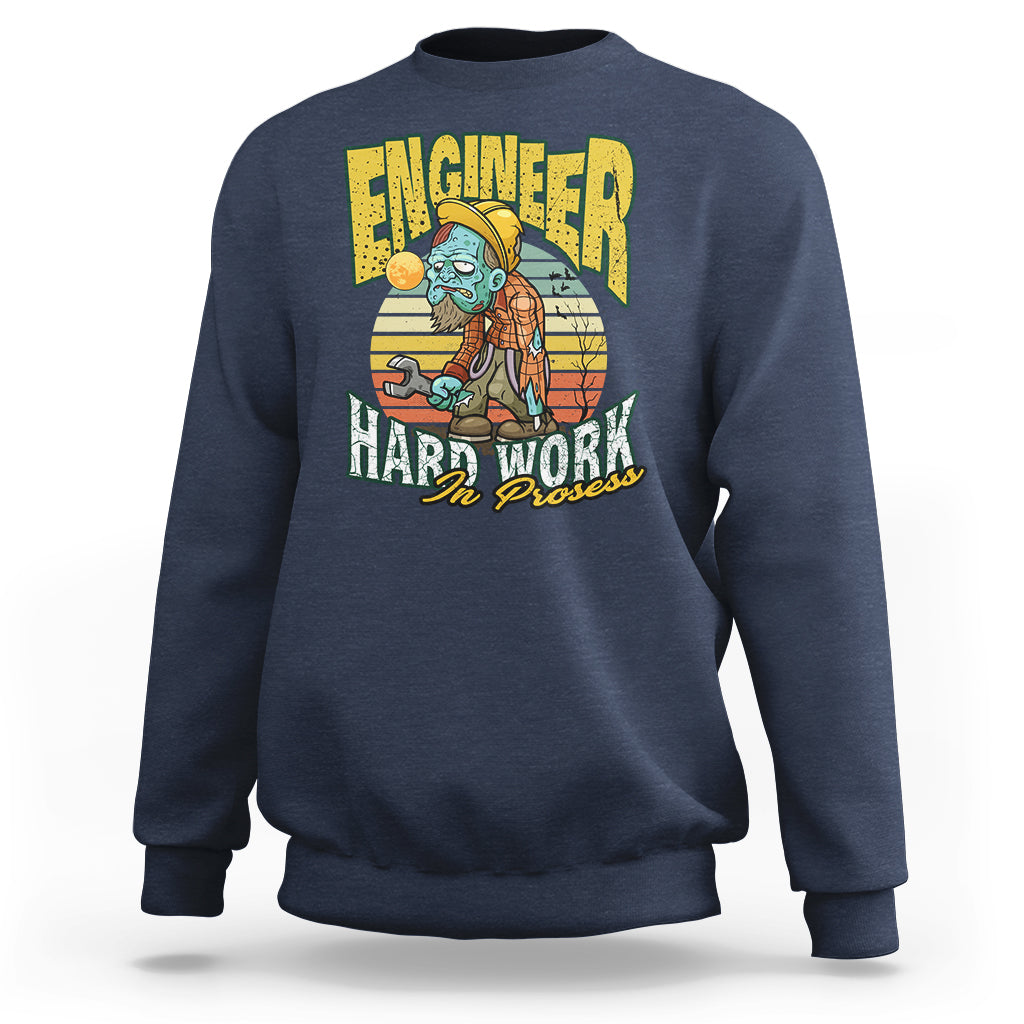 Navy crewneck sweatshirt with front “Engineered Hard Work In Progress” graphic