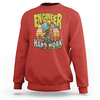 Red crewneck sweatshirt with front “Engineered Hard Work In Progress” graphic