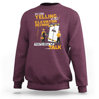 Maroon crewneck sweatshirt with elevator mechanic graphic and bold text on front