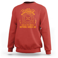 Red crewneck sweatshirt with circular engineer graphic and “NOTHING SHOCK ME” text