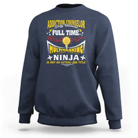 Navy sweatshirt with colorful “Addiction Counselor” and “Multitasking Ninja” text graphic.
