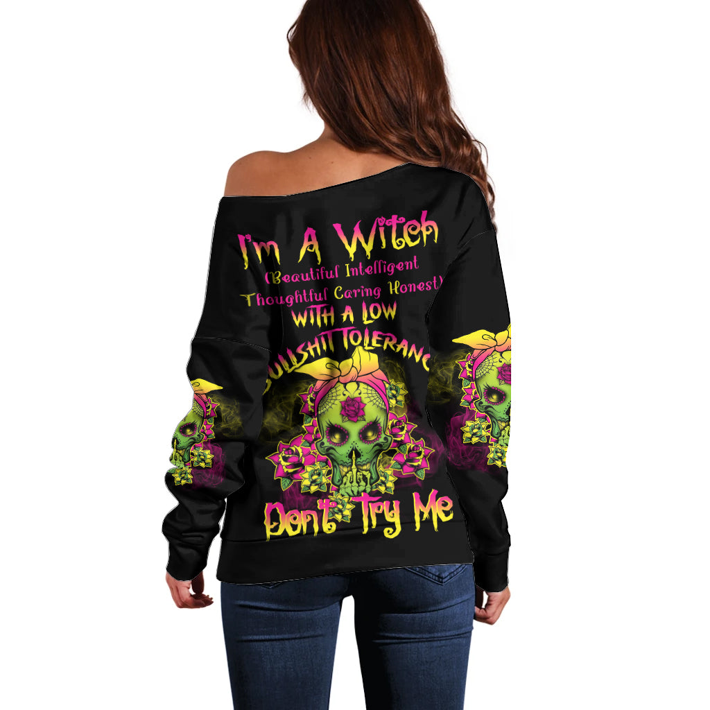 Off-shoulder black sweater with colorful skull graphic and bold back text