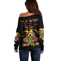 Off-shoulder black sweater with colorful skull graphic and bold back text