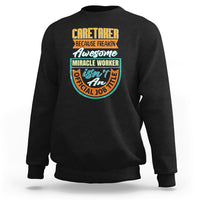 Black crewneck sweatshirt with colorful “Caretaker” miracle worker graphic