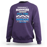 Purple crewneck sweatshirt with "Emergency Manager" "Ninja" text graphic on the front