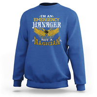 Royal blue sweatshirt with 'Emergency Manager' and 'Not a Magician' eagle graphic on front.