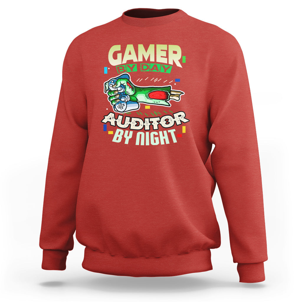 Red crewneck sweatshirt with “GAMER BY DAY” and “AUDITOR BY NIGHT” chest graphic.