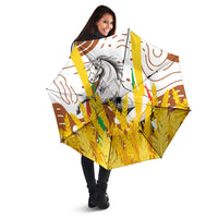 Abstract umbrella with white, brown, and yellow pattern, held open