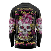 Black long-sleeve graphic shirt, multicolor warning text with skulls and pink flowers