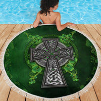 Round green beach blanket showing Celtic cross and shamrock floral pattern with white fringe