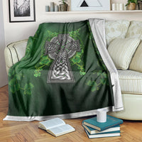 Green Irish cross and shamrock floral blanket draped over a couch with white trim