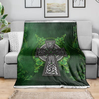 Green Irish cross and shamrock floral blanket spread on a sofa, bordered edge visible