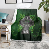 Green Irish cross and shamrock floral blanket over a gray chair, white border at bottom