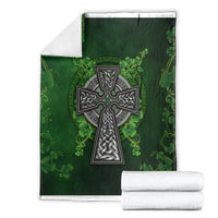 Green Irish cross and shamrock floral blanket folded with white towels, cross centered