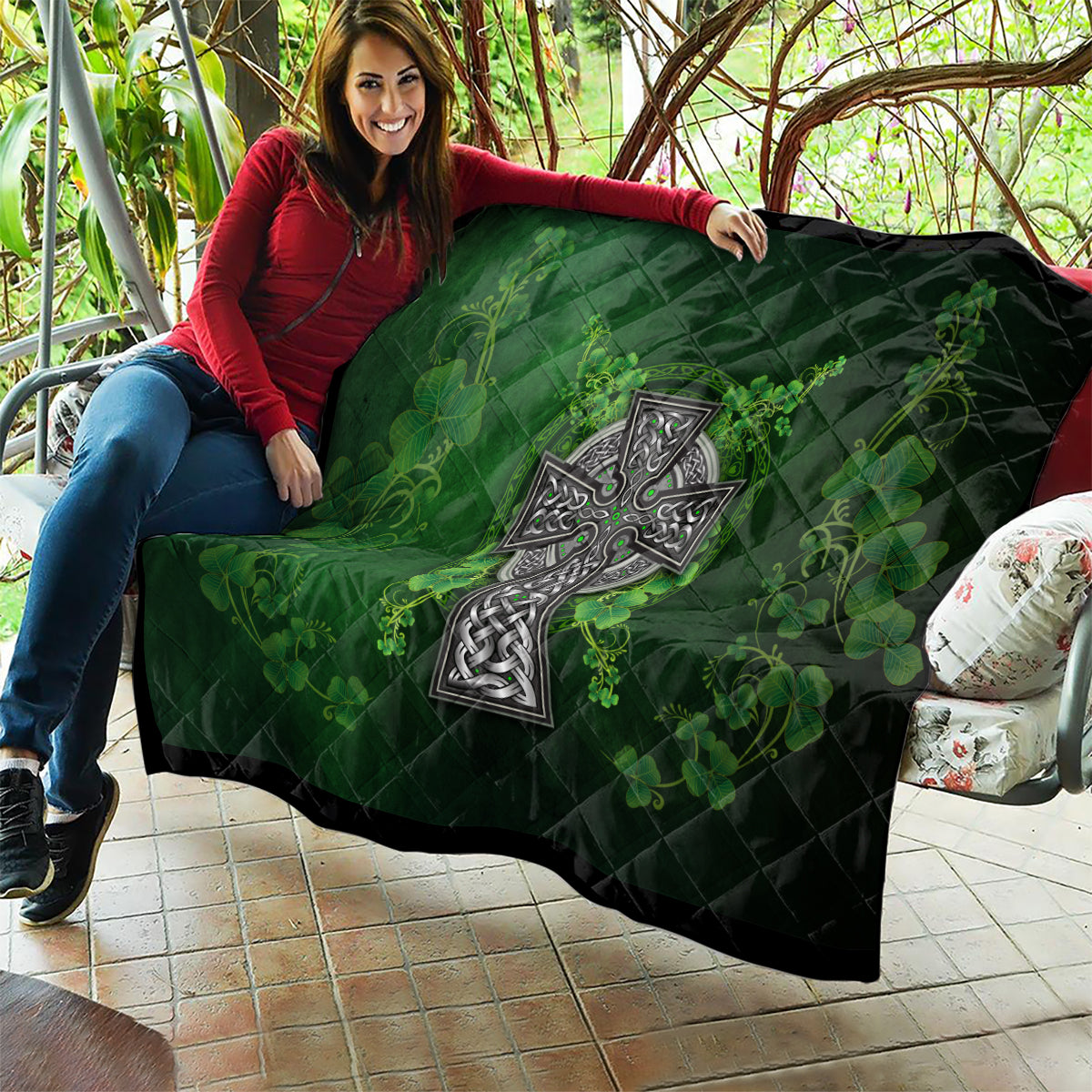 Dark green quilt draped over arm with Celtic cross design and shamrock floral vine pattern