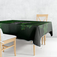 Rectangular green tablecloth with shamrock and cross design, draped over table edge.