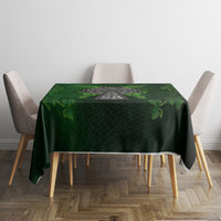 Green rectangular tablecloth with Irish cross and leaf pattern, laid on dining table.