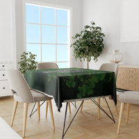Green tablecloth with shamrock and cross motif across dining table with chairs.