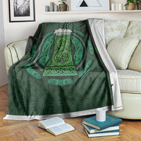 Green Celtic circle patterned blanket with ornate beer-cup style design, draped on a sofa