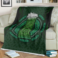 Green celtic circle blanket with detailed emblem at center, draped over a striped sofa