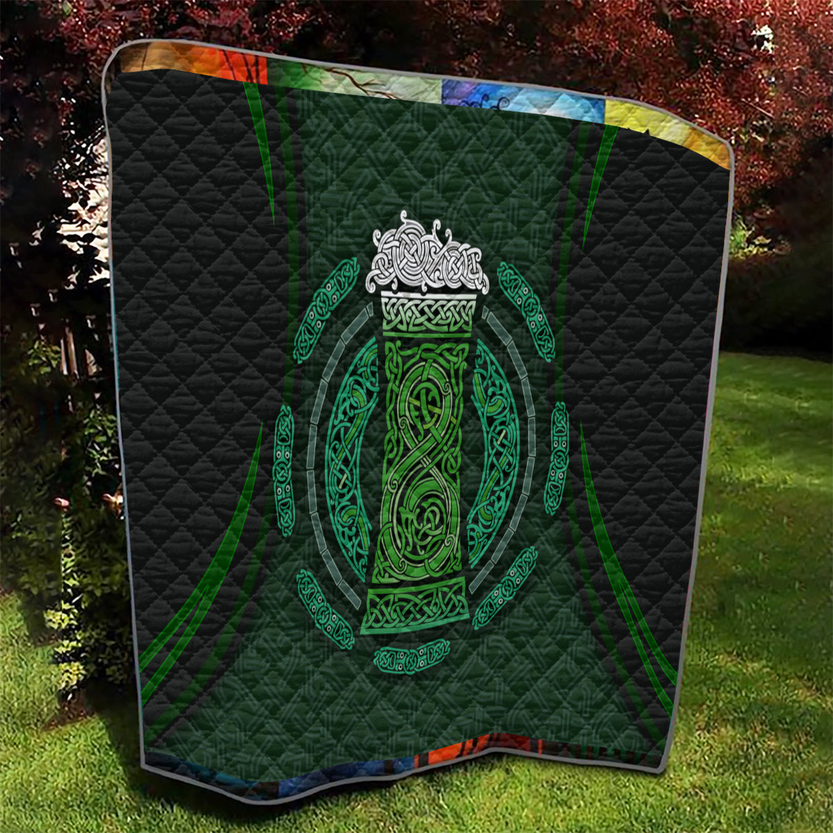Black quilt blanket featuring centered green Celtic circle crest with ornate filigree, quilted
