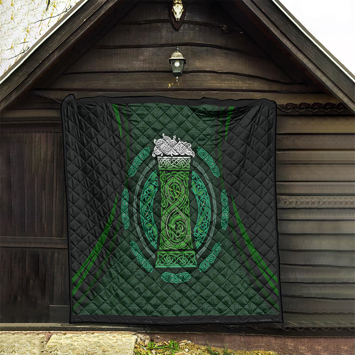 Black quilt wall hanging with green Celtic circle crest, quilted diamonds and ornate border lines