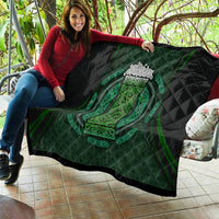 Black quilt blanket draped over sofa with green Celtic oval emblem and circular filigree design