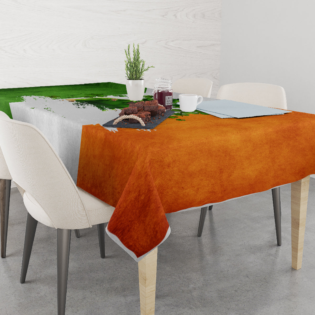 Multicolor tablecloth featuring green, orange, and white shamrocks; overhanging corners.