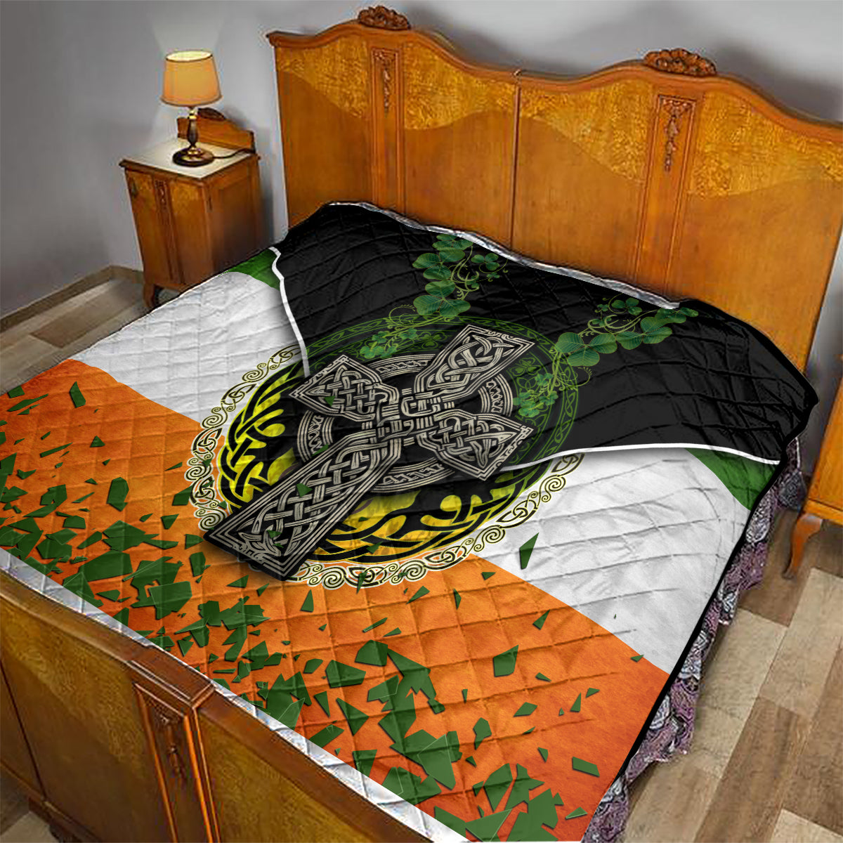 Irish cross quilt laid on bed with black quilted fabric, green shamrock center and orange lower panel