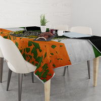 Irish-themed tablecloth on dining table with orange green shamrock print and black border.