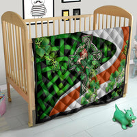 Multicolor quilt for crib with white cross motif, green clovers, and orange diagonal panels