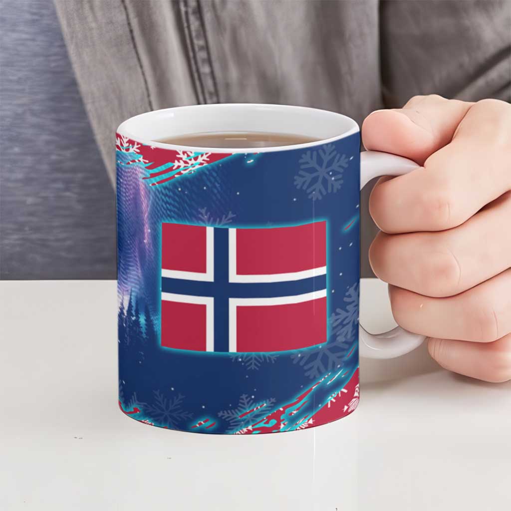 Blue ceramic mug with Norwegian flag graphic and snowflakes, held in a hand