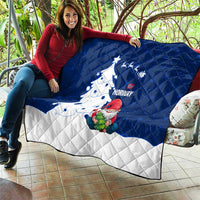 Blue and white quilt draped on seating with Norway text, gnome Santa, and Christmas tree