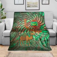 Green tie-dye throw blanket draped on couch with camel and Mauritania crescent emblem