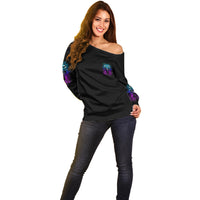 Off-shoulder black sweater with small purple/blue chest graphic and left sleeve art
