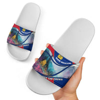 White slide sandals with multicolor mountain graphic band and crown emblem, hand-held view