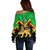 Off-shoulder sweater with green/black crest graphic and lion, long sleeves.