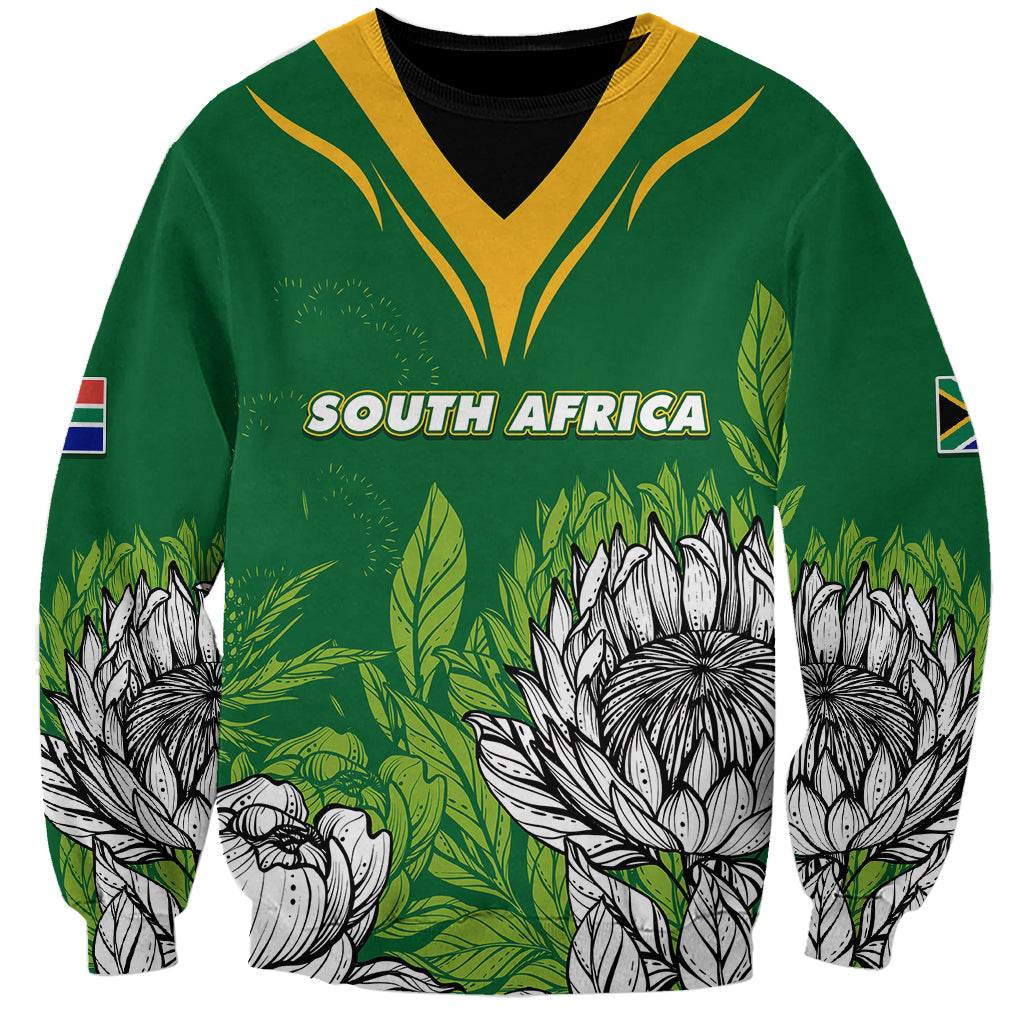 Green sweatshirt with yellow V yoke, South Africa print, protea flowers, sleeve flag patches