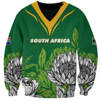 Green unisex sweatshirt with SOUTH AFRICA text, protea print, and flag sleeve patches