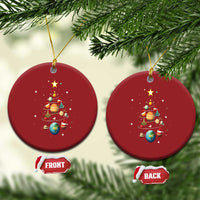 Two red round Christmas ornaments with solar system and Christmas tree artwork, hanging from strings