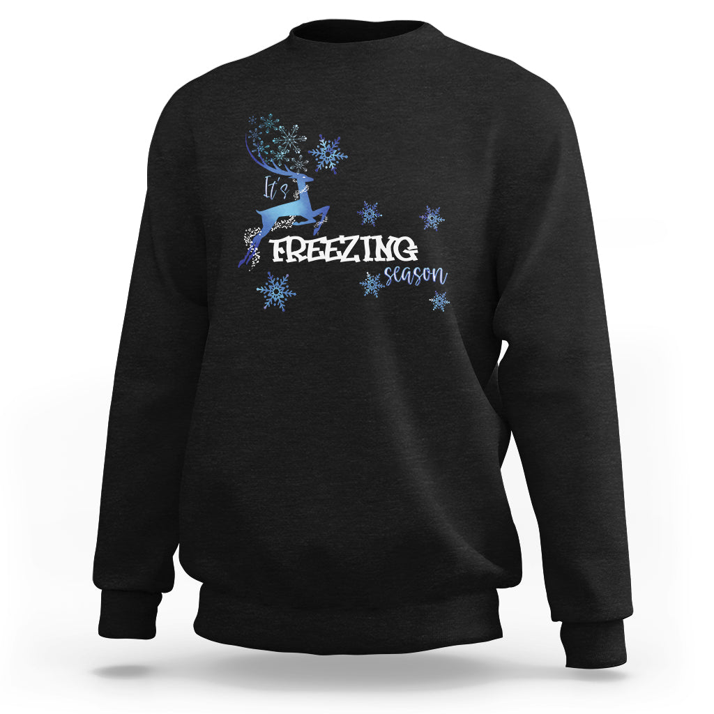 Black crewneck sweatshirt with blue reindeer and snowflake graphic, “Freezing Season”