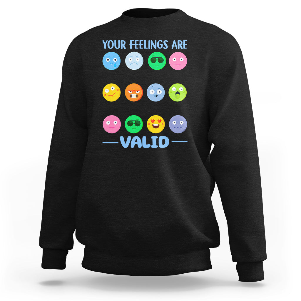 Black sweatshirt with “YOUR FEELINGS ARE VALID” text and colorful emotion-face graphics.