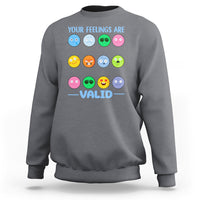 Charcoal gray sweatshirt with “YOUR FEELINGS ARE VALID” text and colorful emotion-face graphics.