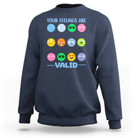 Navy sweatshirt with “YOUR FEELINGS ARE VALID” text and colorful emotion-face graphics.